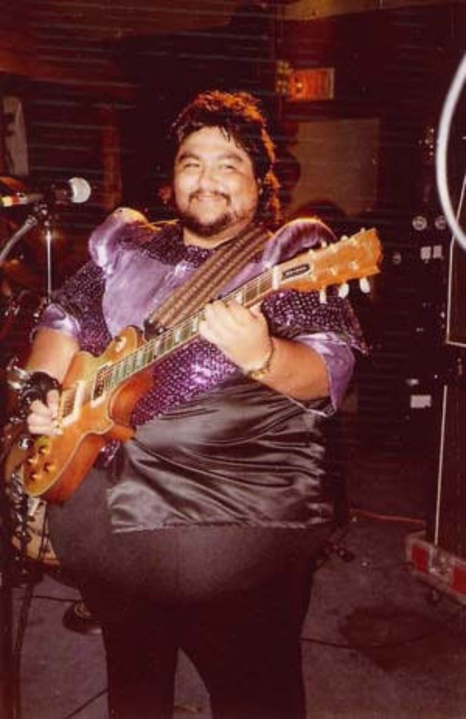 Jimmy Gonzalez of Grupo Mazz smiling while playing guitar
