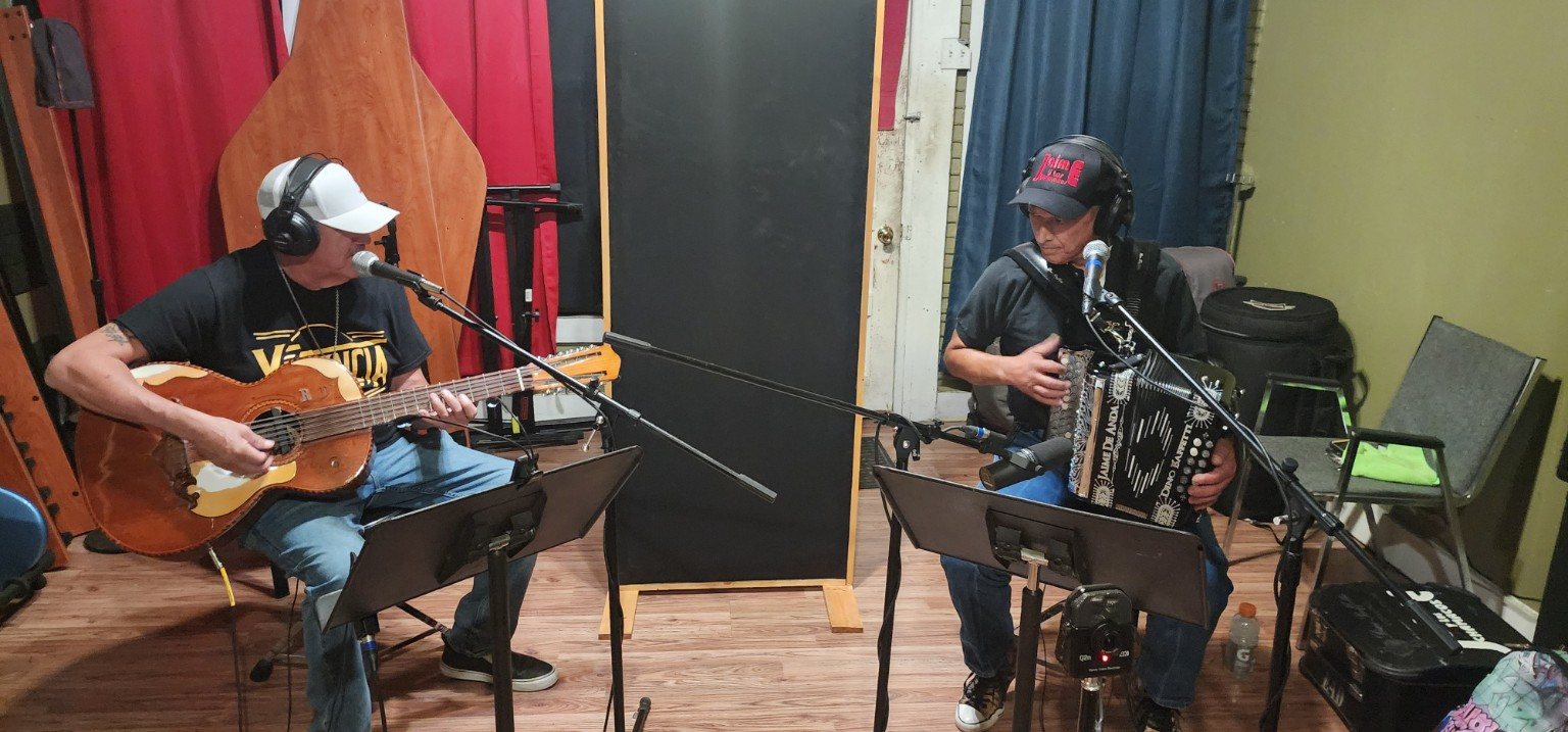 Two musicians recording in a studio setting